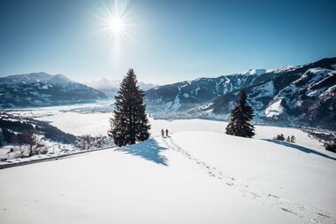 Winter scene with snowshoeing in a snowy mountain landscape under sunny skies. | © Zell am See-Kaprun Tourismus