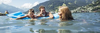 Family enjoying water activities on a lake with mountains in the background on a sunny day. | © Zell am See-Kaprun Tourismus