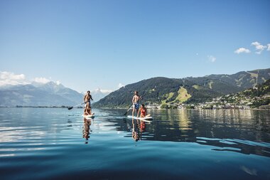 People stand-up paddling on Lake Zeller with mountainous scenery in the background. | © Zell am See-Kaprun Tourismus