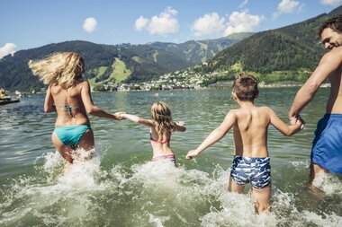 Family enjoying water fun at Lake Zell with mountain scenery in the background. | © Zell am See-Kaprun Tourismus