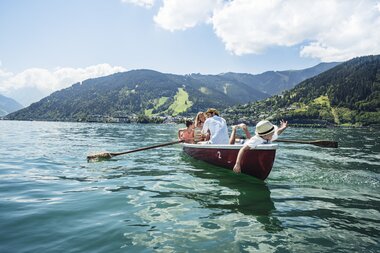 A family paddles a rowboat on Lake Zell surrounded by mountainous scenery. | © Zell am See-Kaprun Tourismus