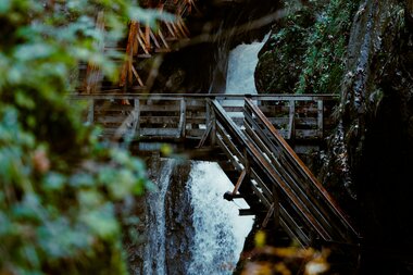 View of Sigmund Thun Gorge with waterfalls, wooden bridges, and surrounding rocks in a forested setting. | © Zell am See-Kaprun Tourismus