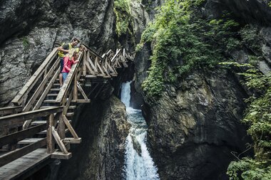 Visitors on a wooden walkway in the Sigmund Thun Gorge, surrounded by steep rocks and waterfalls. | © Zell am See-Kaprun Tourismus