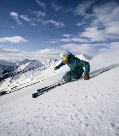 Skier skier in deep snow on a mountain slope under clear weather. | © saalbach.com, Stefan Voitl