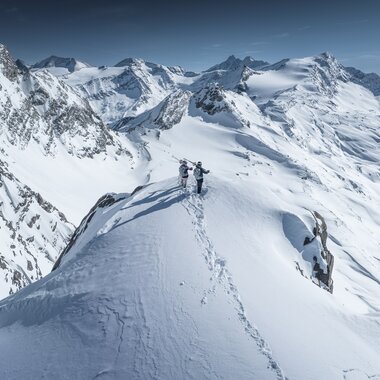 Mountaineers on snowy summit in the Austrian Alps with a wide view of snow-covered mountains. | © Kitzsteinhorn