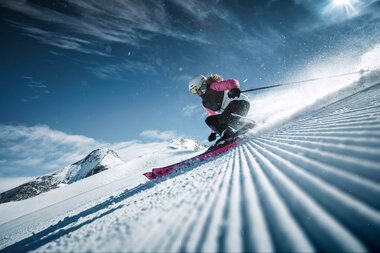 Skier person on groomed slope at Kitzsteinhorn in snowy landscape with mountains in the background, sunny weather. | © Kitzsteinhorn