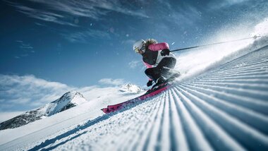 Skier person on groomed slope at Kitzsteinhorn in snowy landscape with mountains in the background, sunny weather. | © Kitzsteinhorn