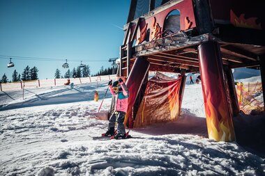 Ski activity under a Dragon Land attraction, children in winter sports gear, sunny weather, snowy landscape, ski resort. | © Zell am See-Kaprun Tourismus