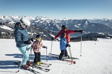 Family skiing on the Schmittenhöhe with mountains in the background. | © Zell am See-Kaprun Tourismus