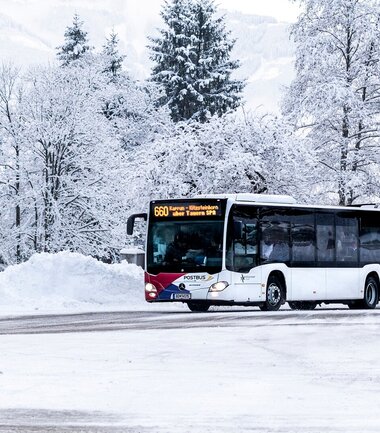 A bus is traveling through a snowy winter landscape with snow-covered trees. | © Kitzsteinhorn