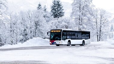 A bus is traveling through a snowy winter landscape with snow-covered trees. | © Kitzsteinhorn