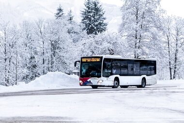 A bus is traveling through a snowy winter landscape with snow-covered trees. | © Kitzsteinhorn