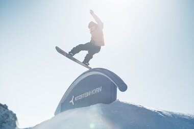 Skier rider performing a trick on a rail at the snowpark on Kitzsteinhorn in Kaprun with the sun in the background. | © Markus Rohrbacher