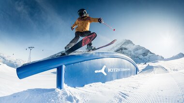 Skier user performing a jump on a snowpark feature at Kitzsteinhorn with snowy mountains in the background. | © Kitzsteinhorn, Markus Rohrbacher