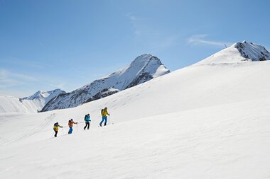 Group hiking in snowy mountain landscape at Kitzsteinhorn on a sunny day. | © Manuel Ferrigato