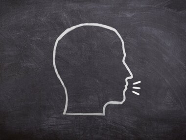 Outline of a head drawing on a chalkboard, representing a speaking person.