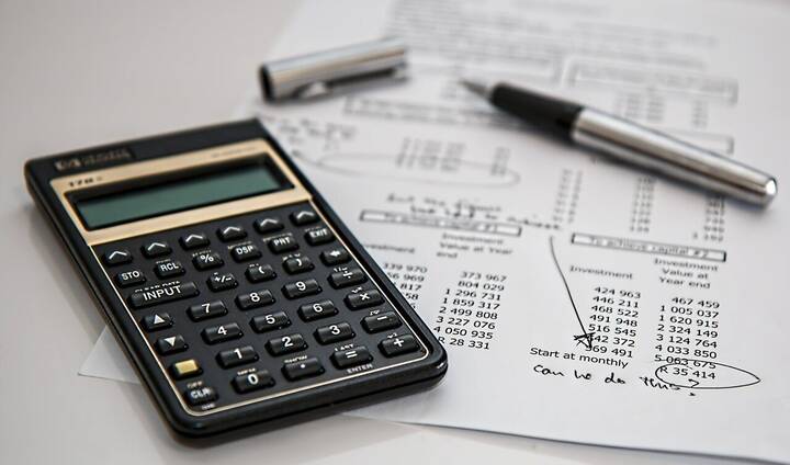Office workspace with calculator, pen, and financial documents on a table.