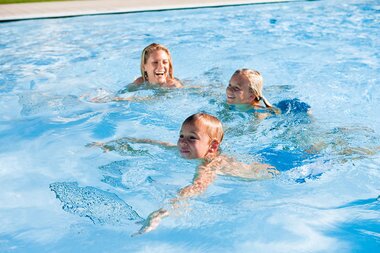 Family swimming in the outdoor pool at Tauern Spa in Kaprun, relaxed and happy. | © TAUERN SPA Zell am See-Kaprun