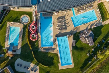 Aerial view of the Tauern Spa outdoor water area with multiple pools and water slides. | © TAUERN SPA Zell am See-Kaprun