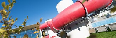 Tube slide in an outdoor water park area with blue sky and green grass | © Gerry Mayr Rohrmoser
