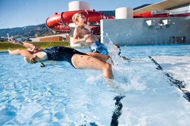 Children playing in the water area of Tauern Spa, with slides in the background and mountains in view. | © Günther Böck